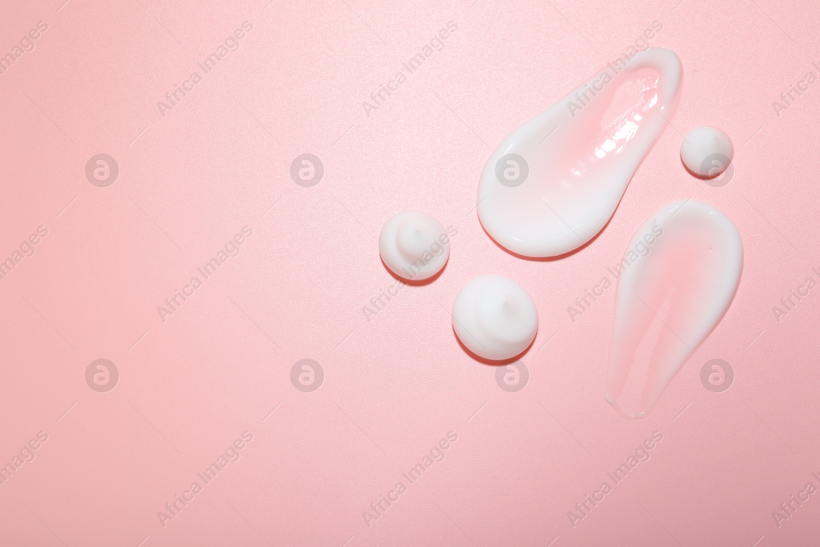 Photo of Cream samples on pink background, top view. Skincare product