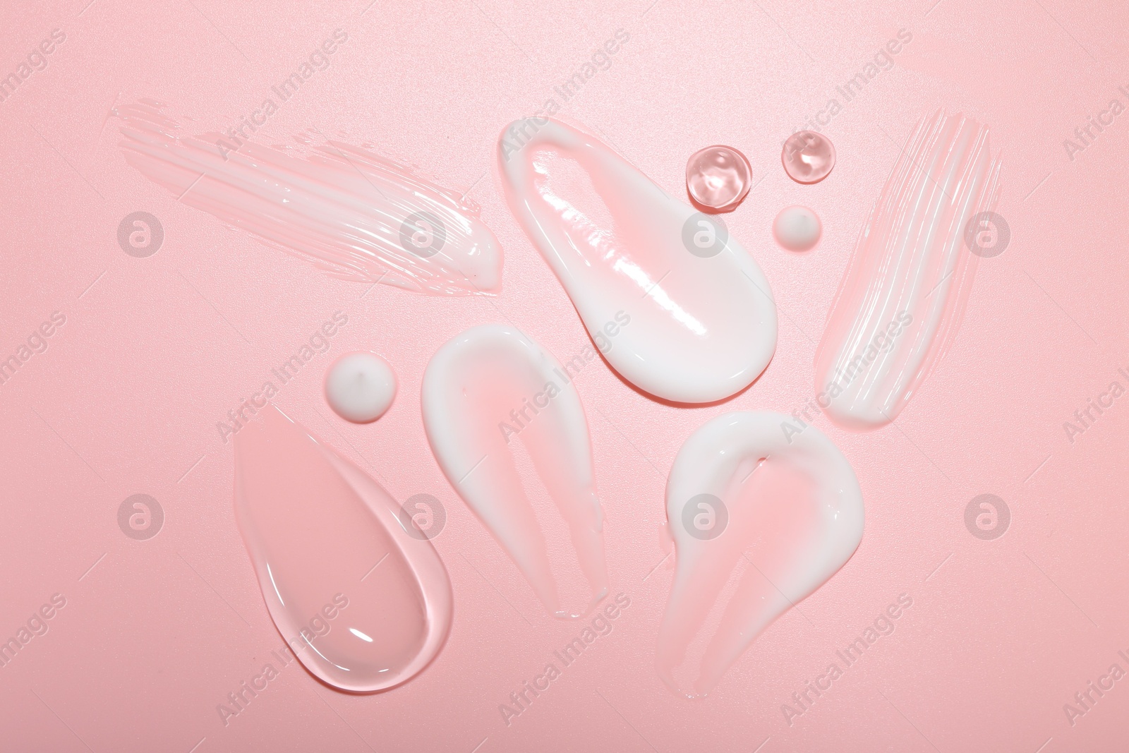 Photo of Cream and gel samples on pink background, top view