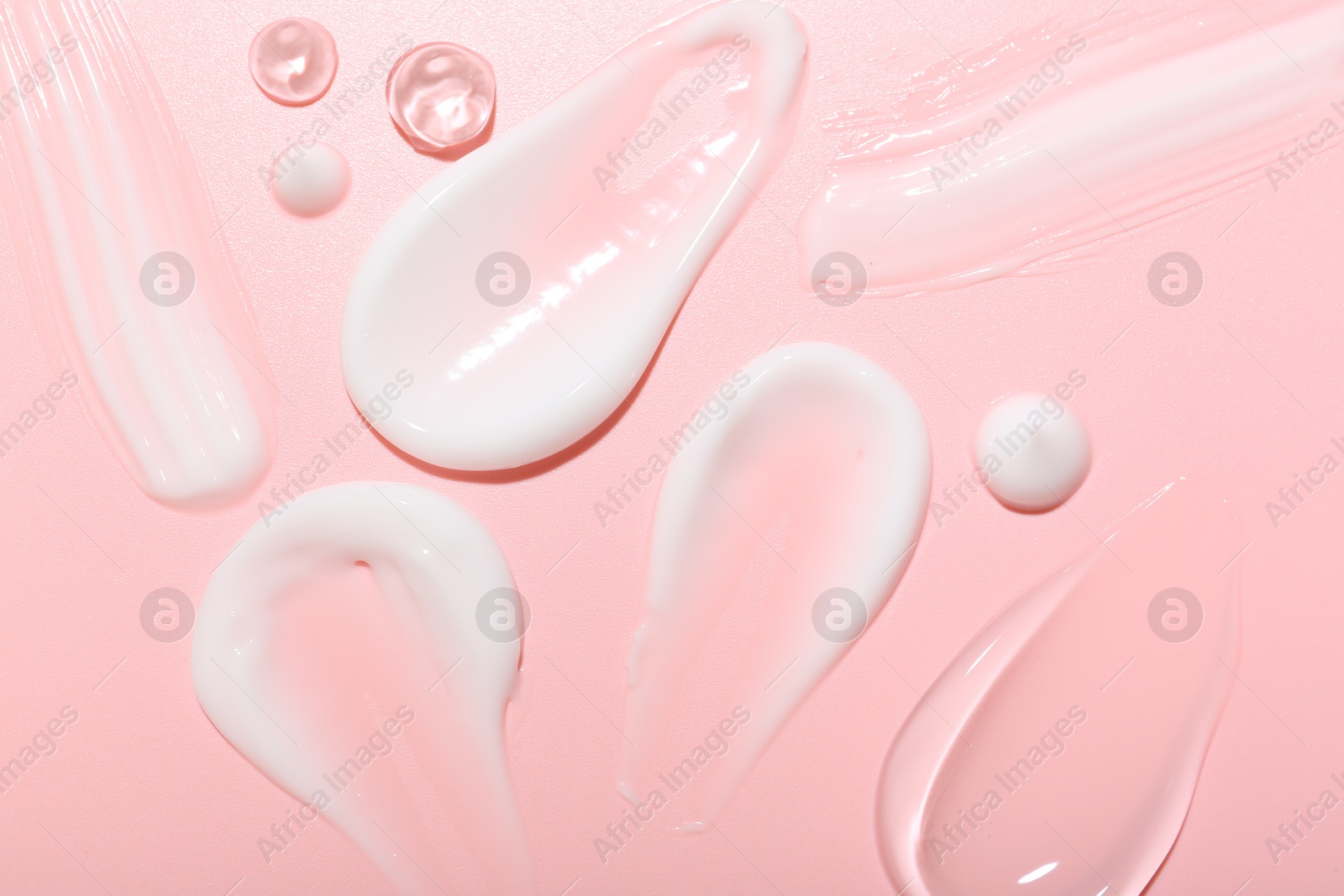 Photo of Cream and gel samples on pink background, top view