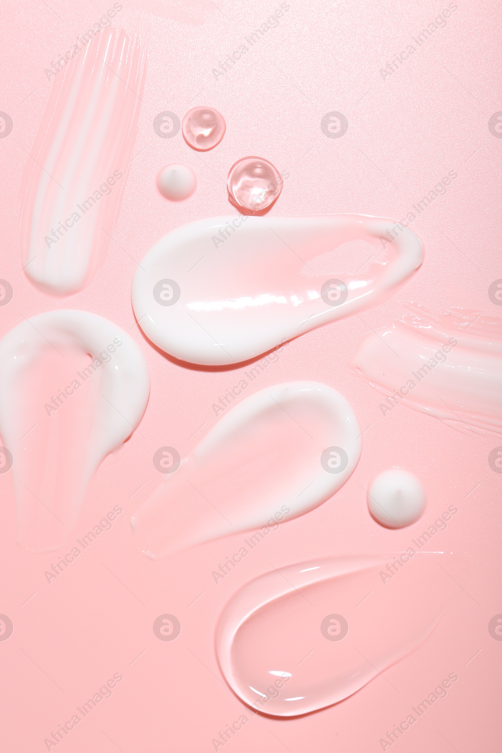 Photo of Cream and gel samples on pink background, top view