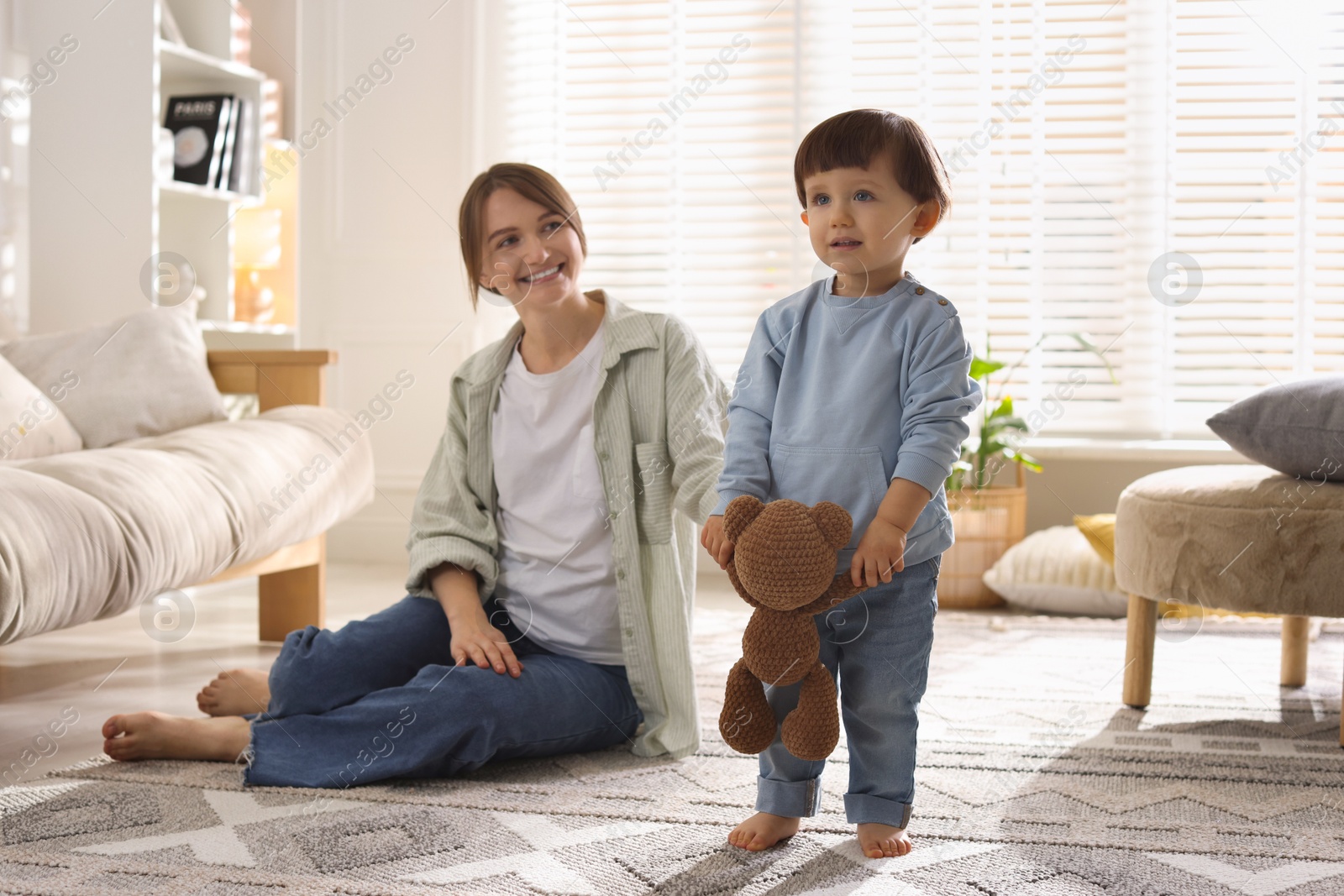 Photo of Happy mother and her cute little son with toy bear at home