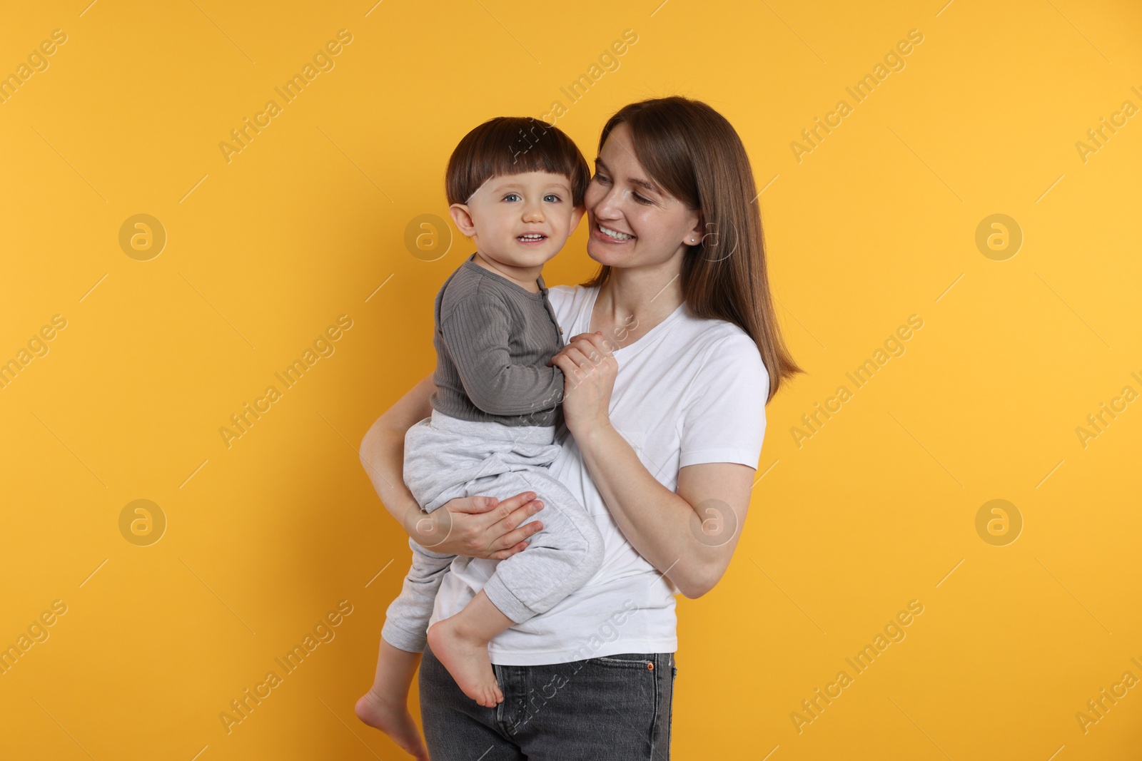 Photo of Happy mother with her cute little son on yellow background