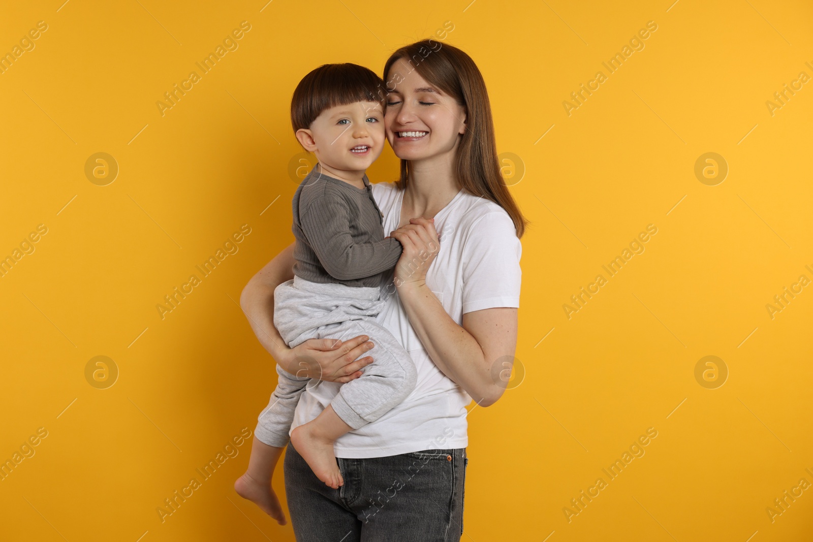 Photo of Happy mother with her cute little son on yellow background