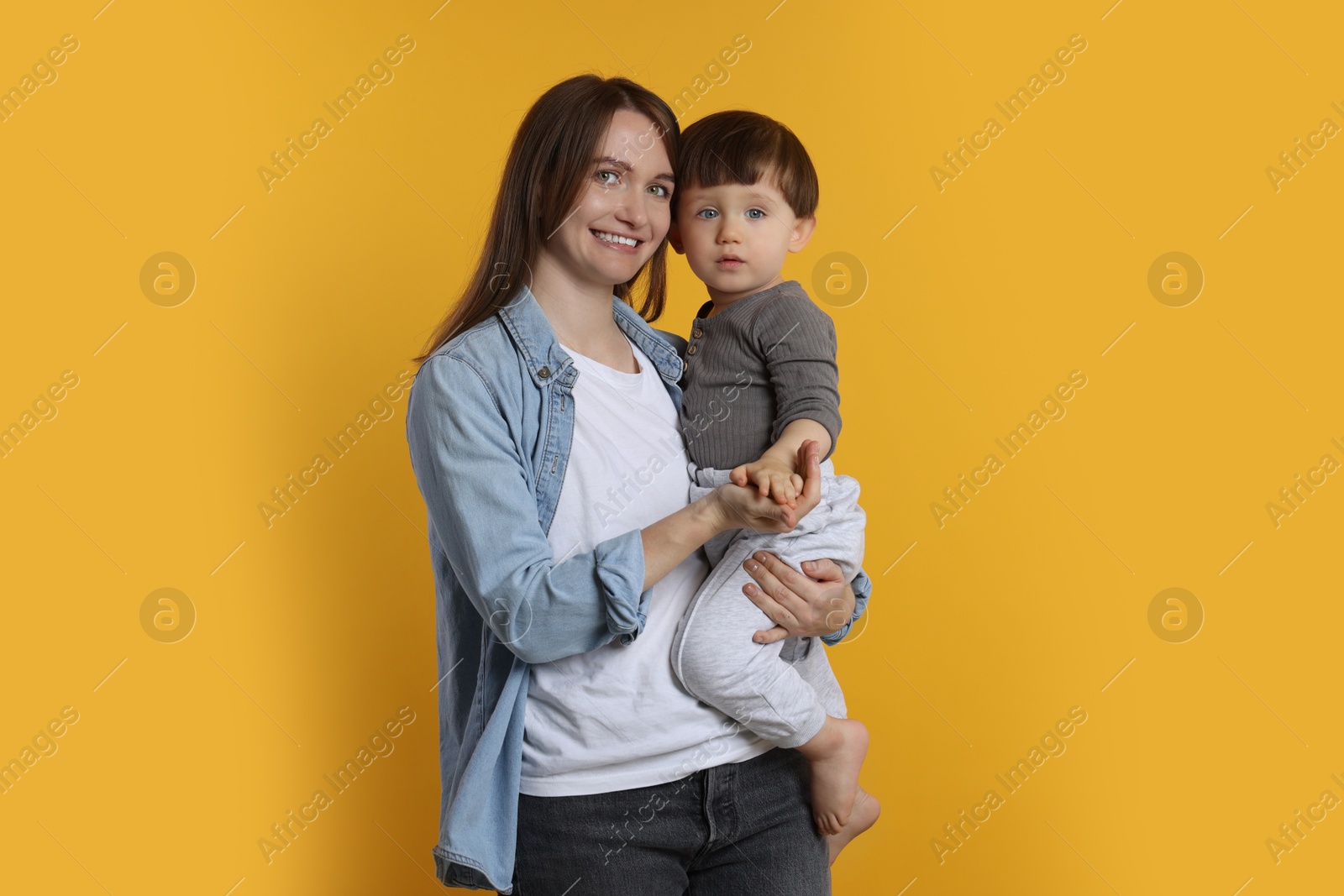 Photo of Happy mother with her cute little son on yellow background