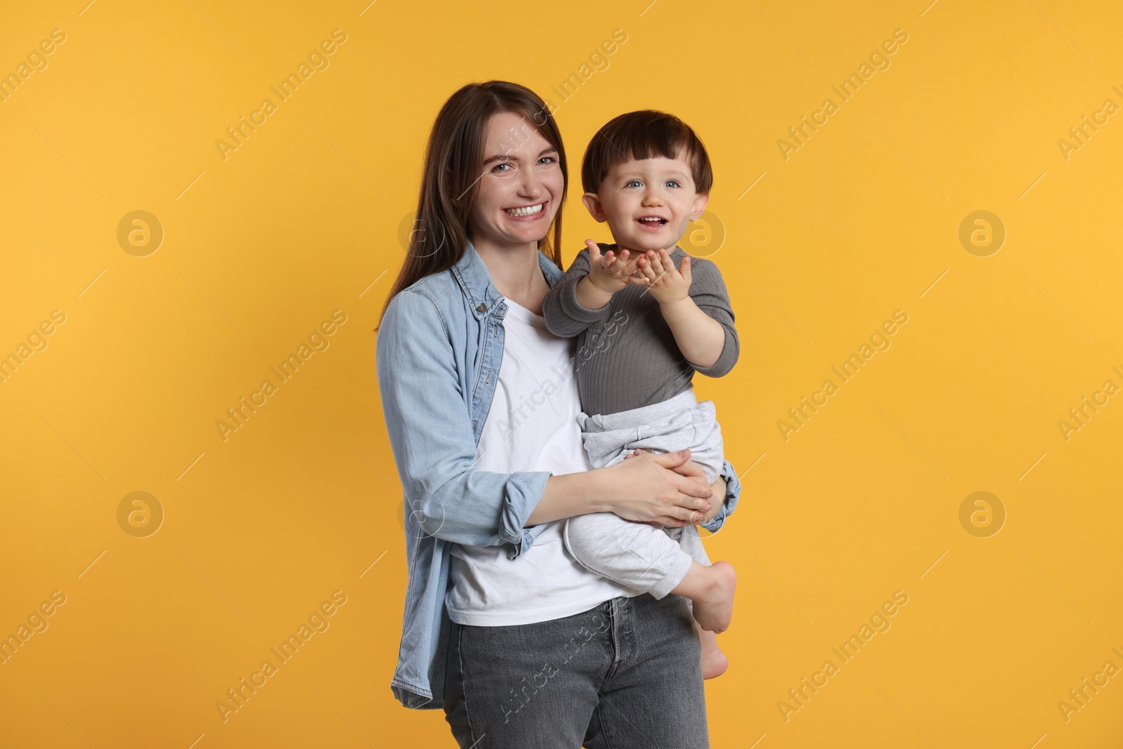 Photo of Happy mother with her cute little son on yellow background