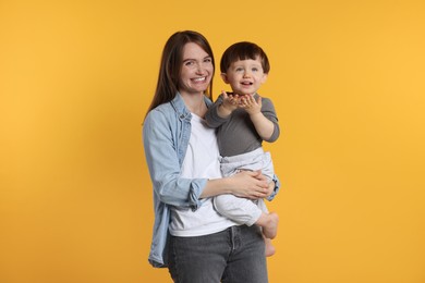 Photo of Happy mother with her cute little son on yellow background