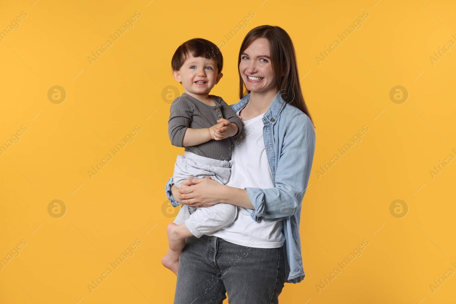 Photo of Happy mother with her cute little son on yellow background