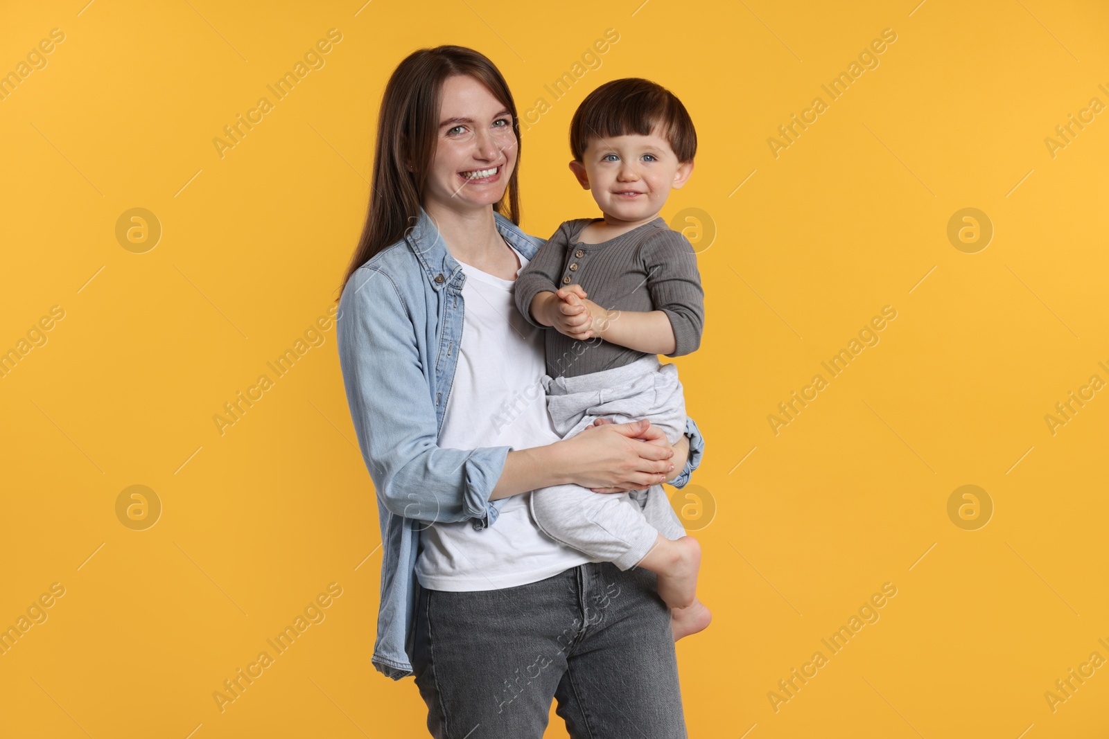 Photo of Happy mother with her cute little son on yellow background