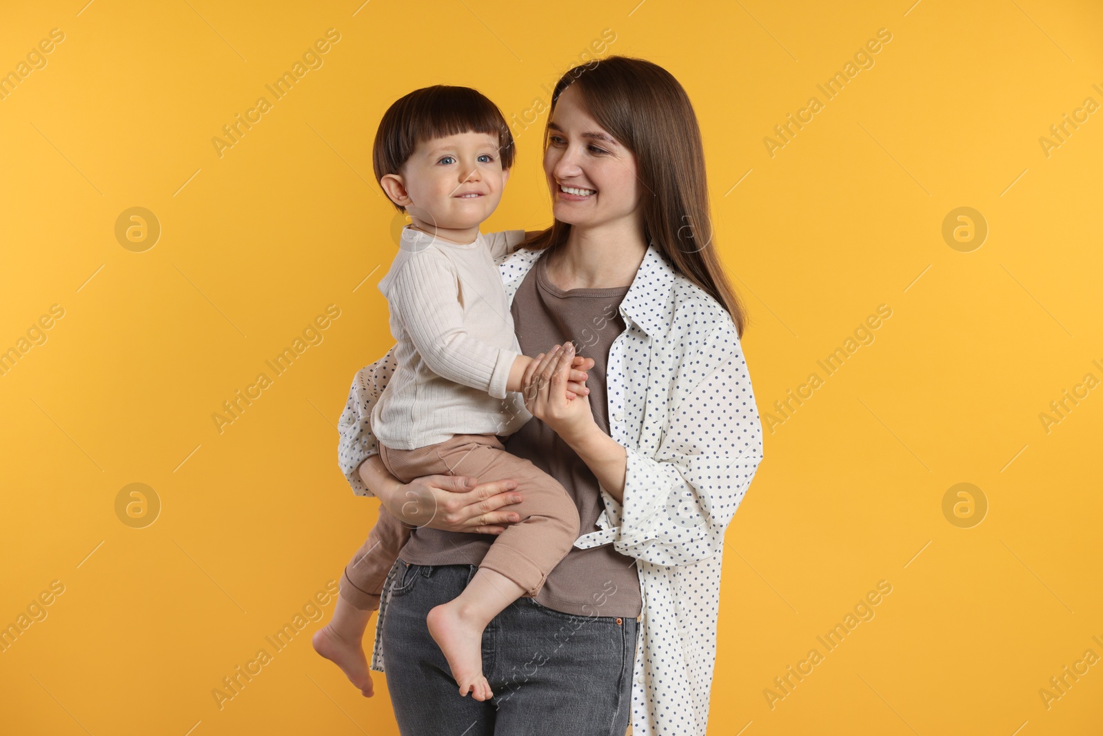 Photo of Happy mother with her cute little son on yellow background