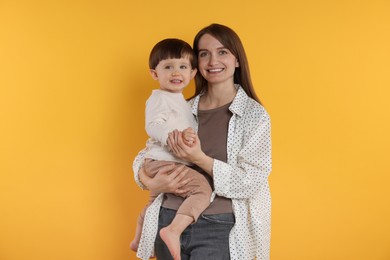 Photo of Happy mother with her cute little son on yellow background