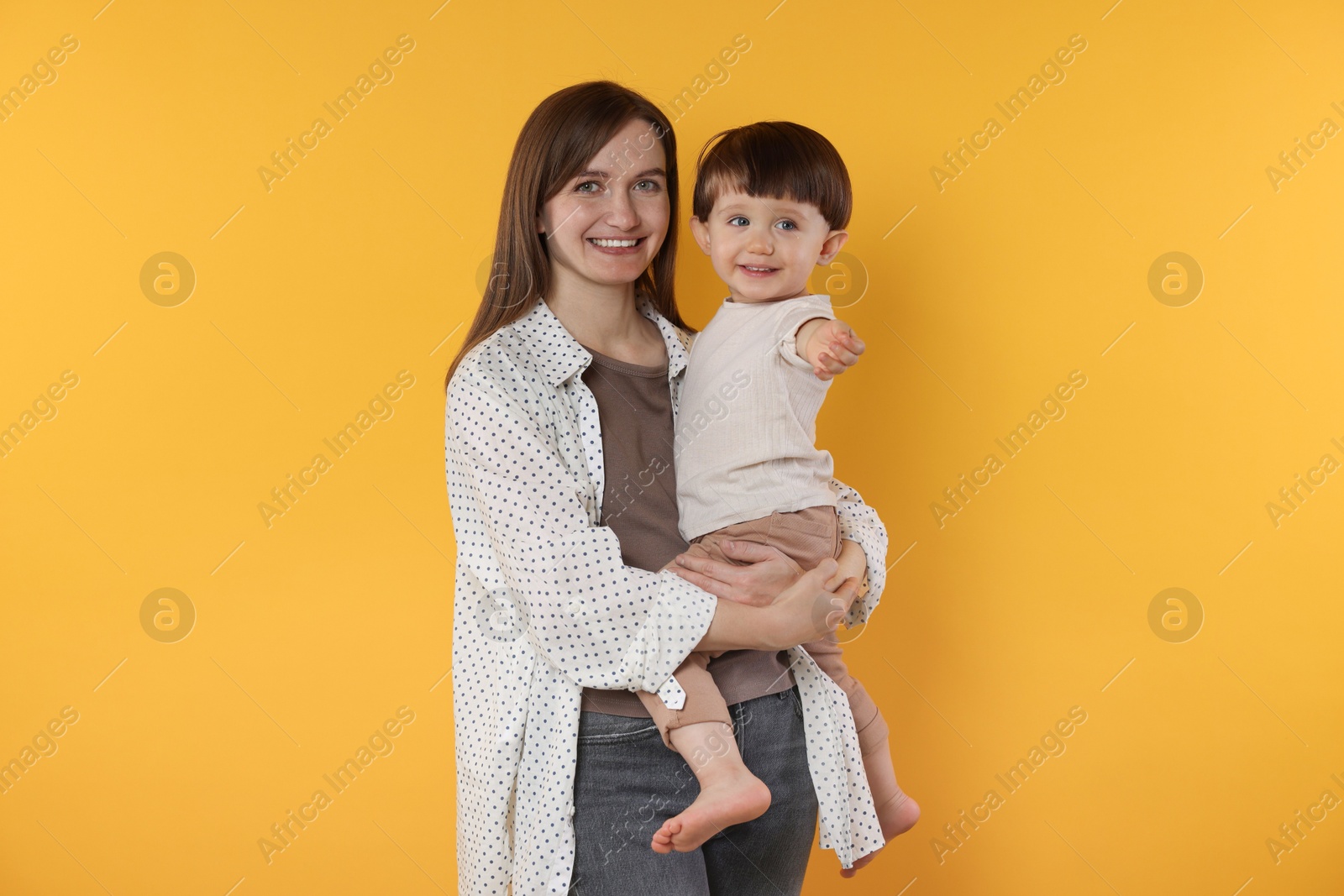 Photo of Happy mother with her cute little son on yellow background