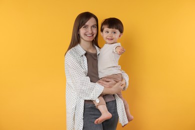 Photo of Happy mother with her cute little son on yellow background