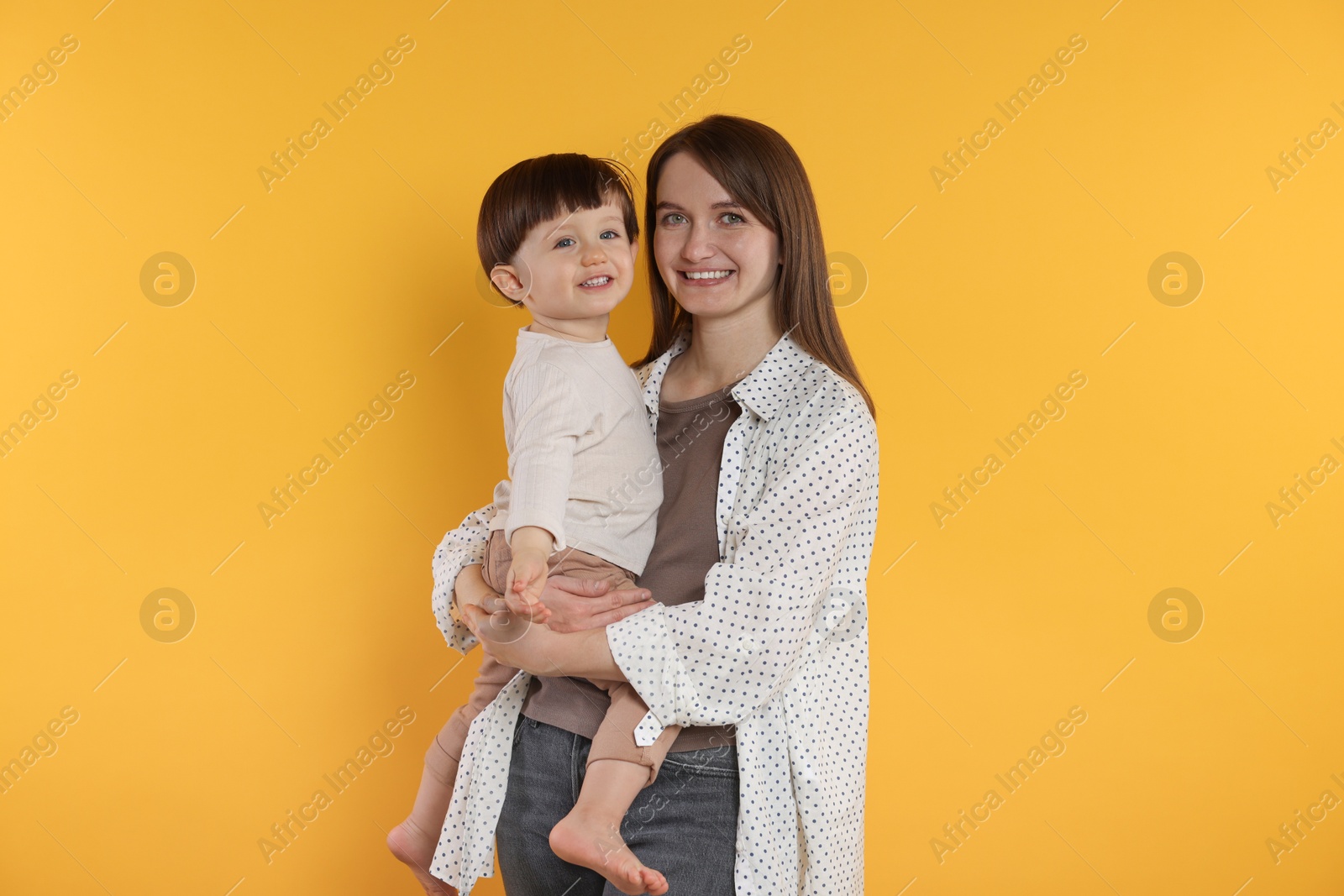 Photo of Happy mother with her cute little son on yellow background