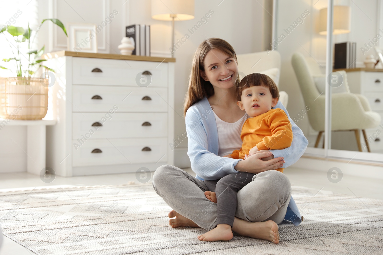 Photo of Happy mother hugging her little son at home. Space for text