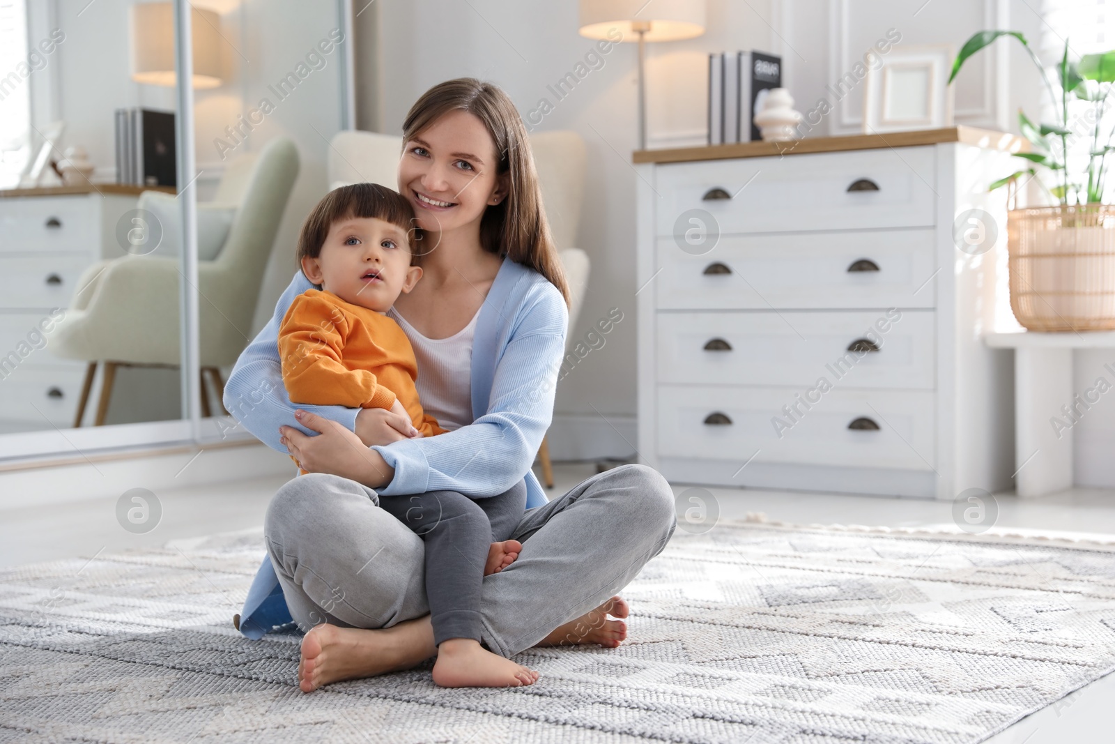 Photo of Happy mother hugging her little son at home. Space for text