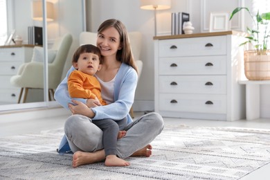 Photo of Happy mother hugging her little son at home. Space for text