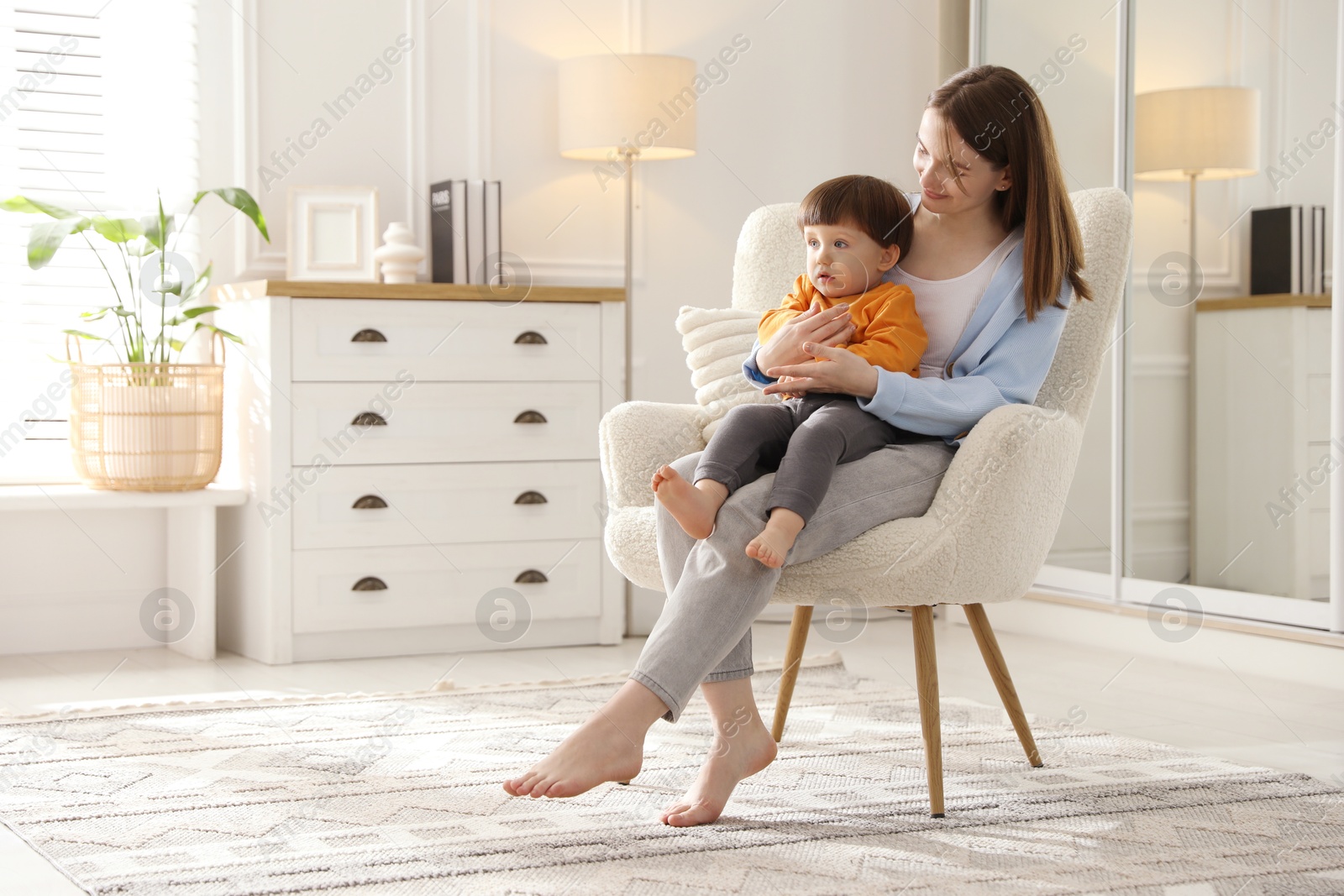 Photo of Mother with her little son sitting on armchair at home. Space for text