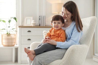 Photo of Happy mother with her little son sitting on armchair at home. Space for text