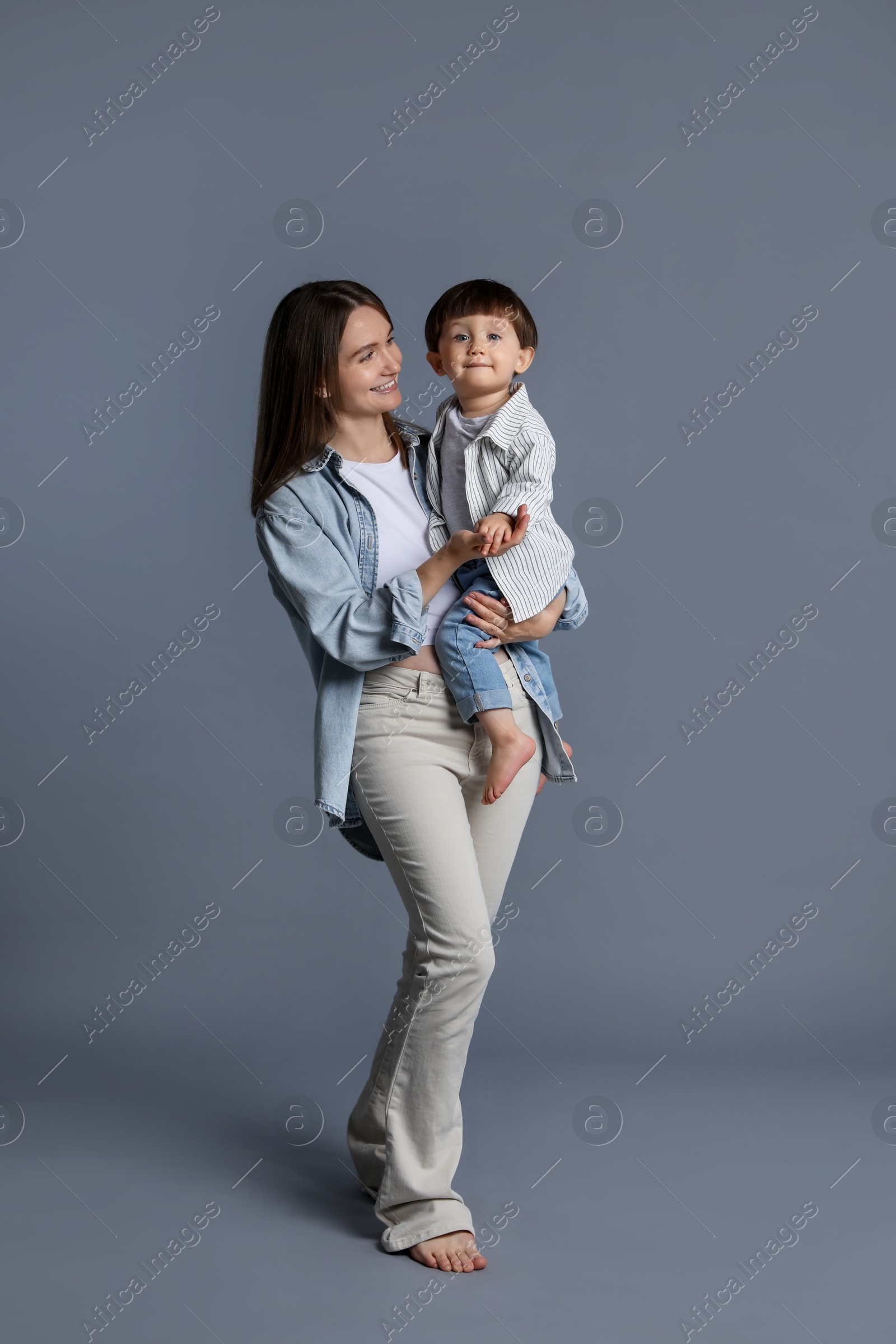 Photo of Happy mother with her little son on grey background