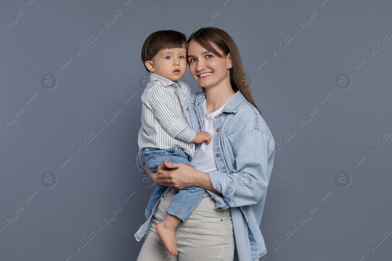 Photo of Happy mother with her little son on grey background