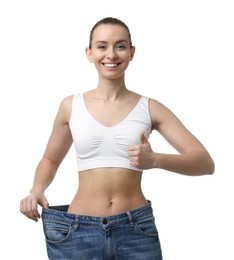 Photo of Weight loss. Happy woman wearing big jeans and showing thumbs up on white background