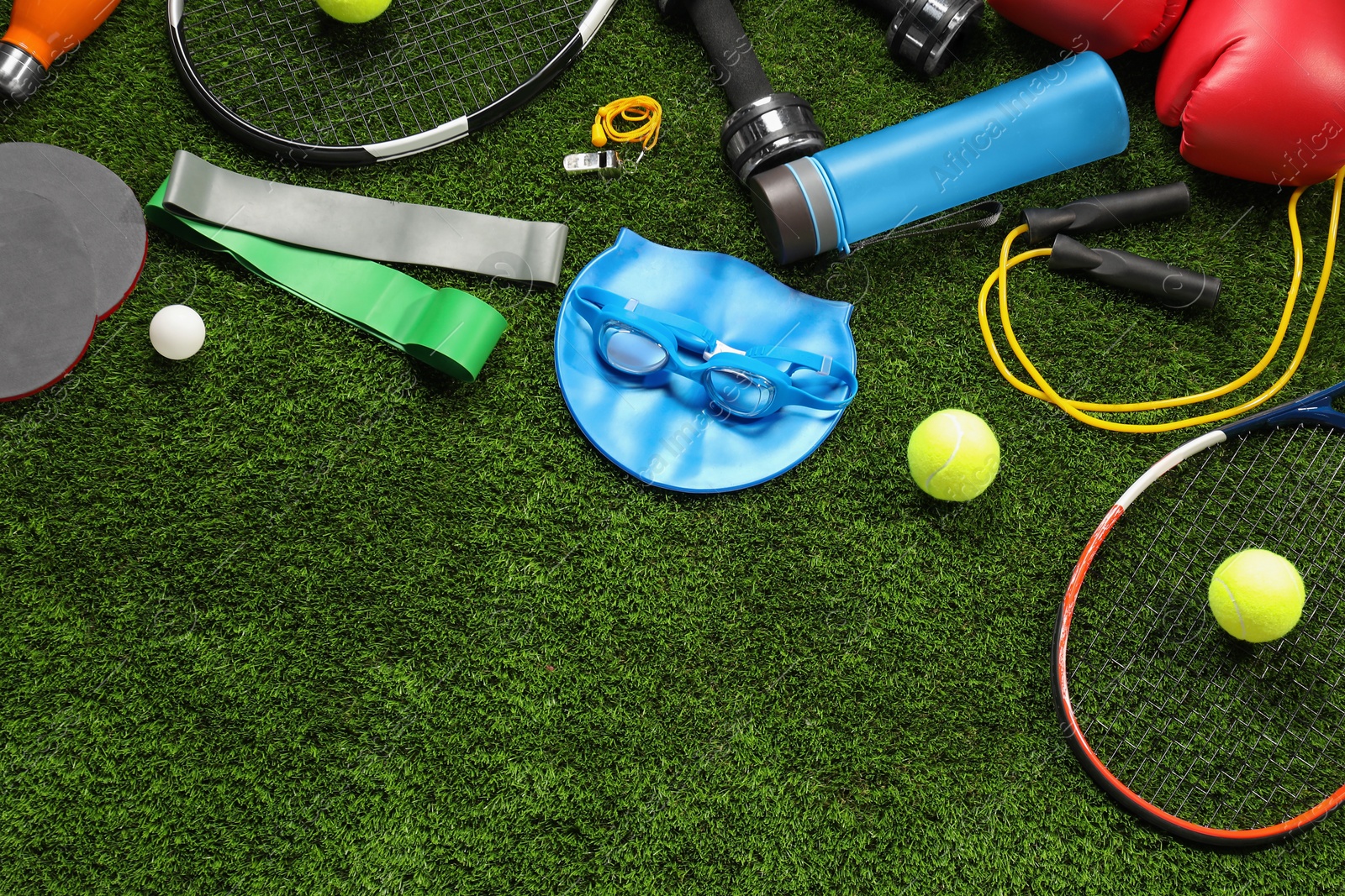 Photo of Different sports equipment on artificial grass, flat lay. Space for text