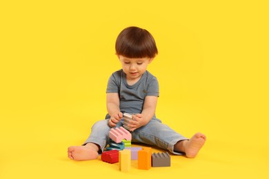 Photo of Cute little boy playing on yellow background