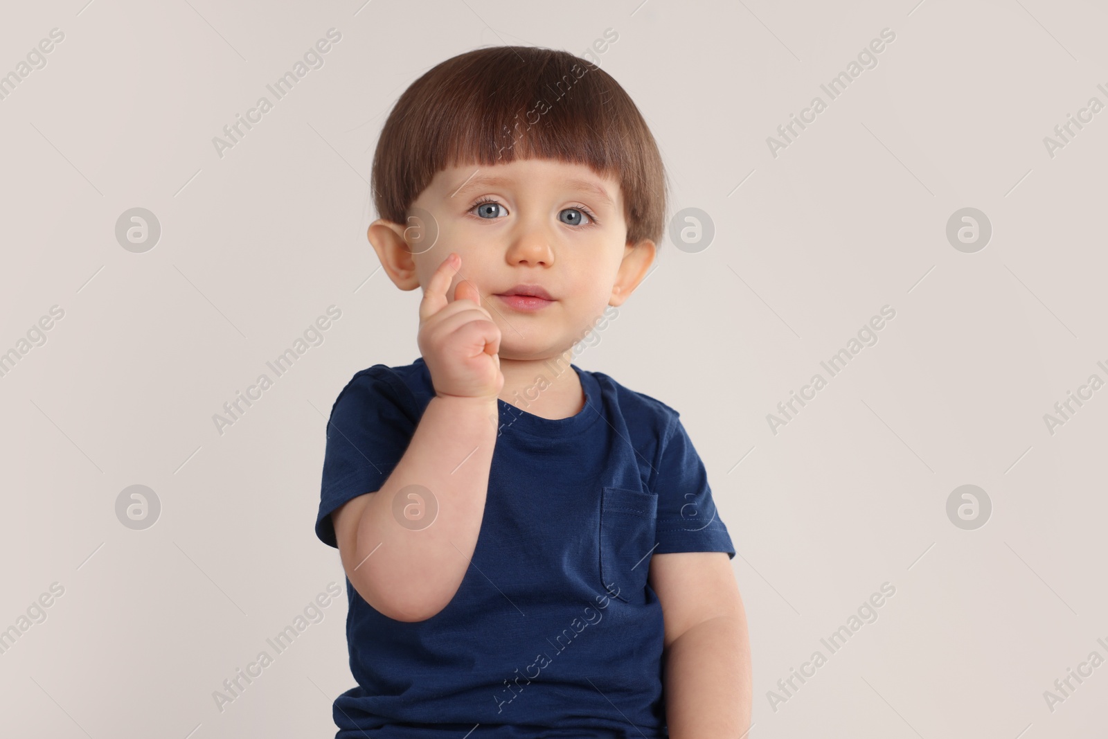 Photo of Portrait of cute little boy on light grey background