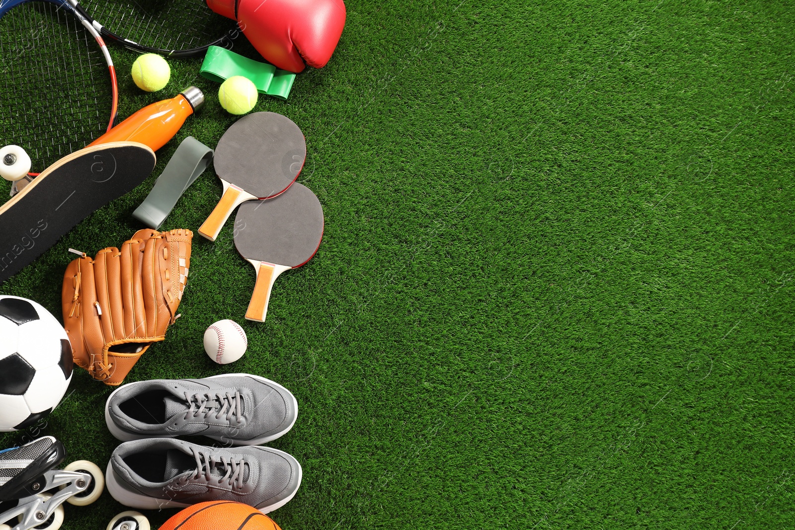 Photo of Different sport equipment on artificial grass, flat lay. Space for text