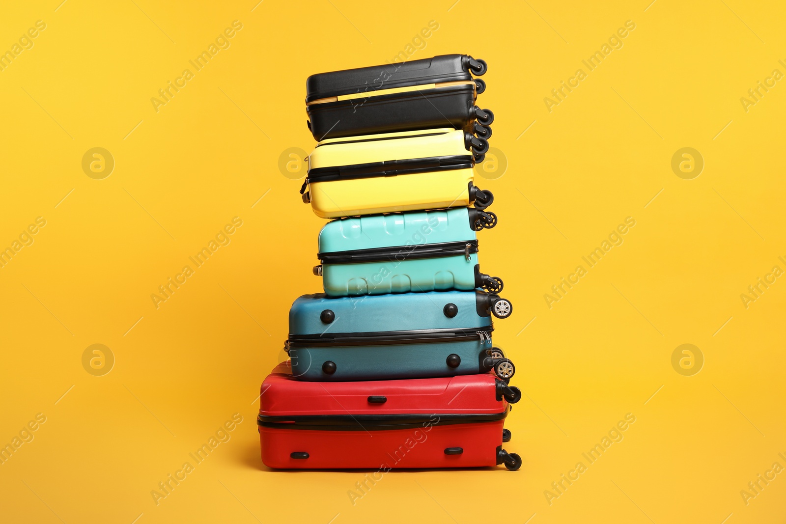 Photo of Stack of colorful suitcases on orange background