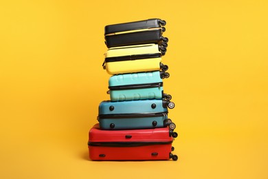 Photo of Stack of colorful suitcases on orange background