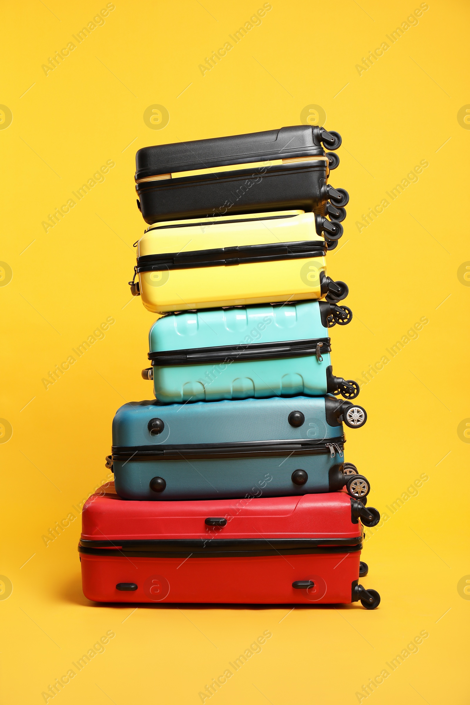 Photo of Stack of colorful suitcases on orange background