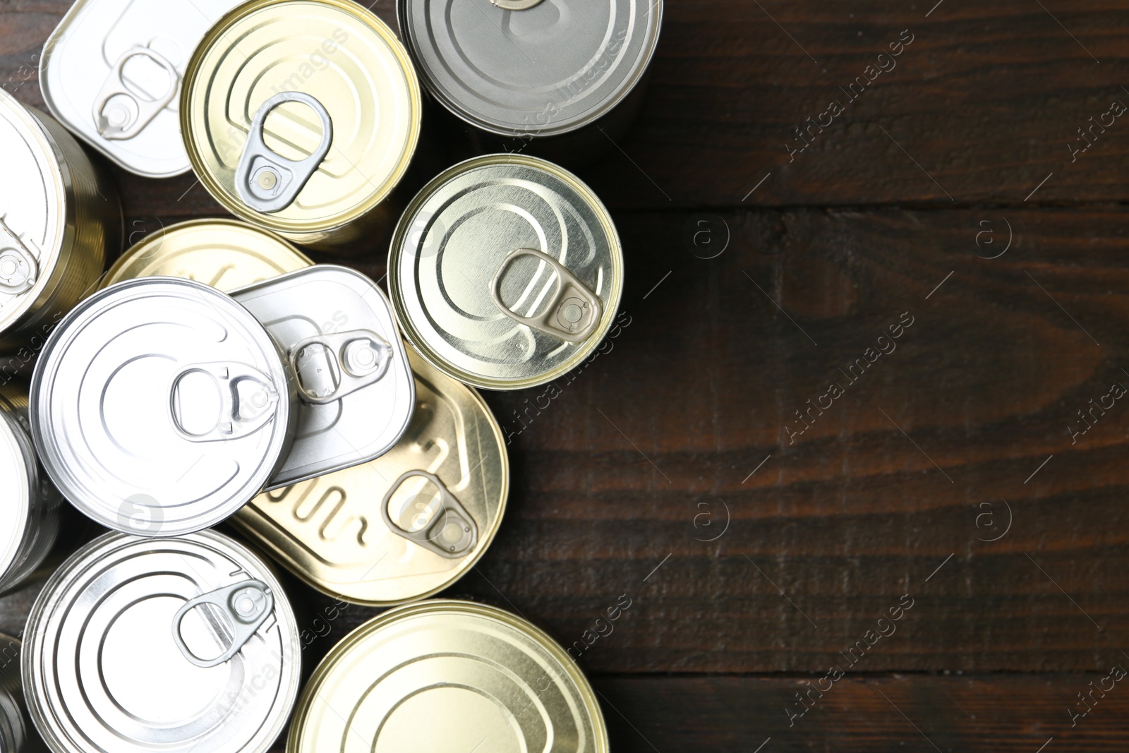 Photo of Many closed tin cans on wooden table, flat lay. Space for text