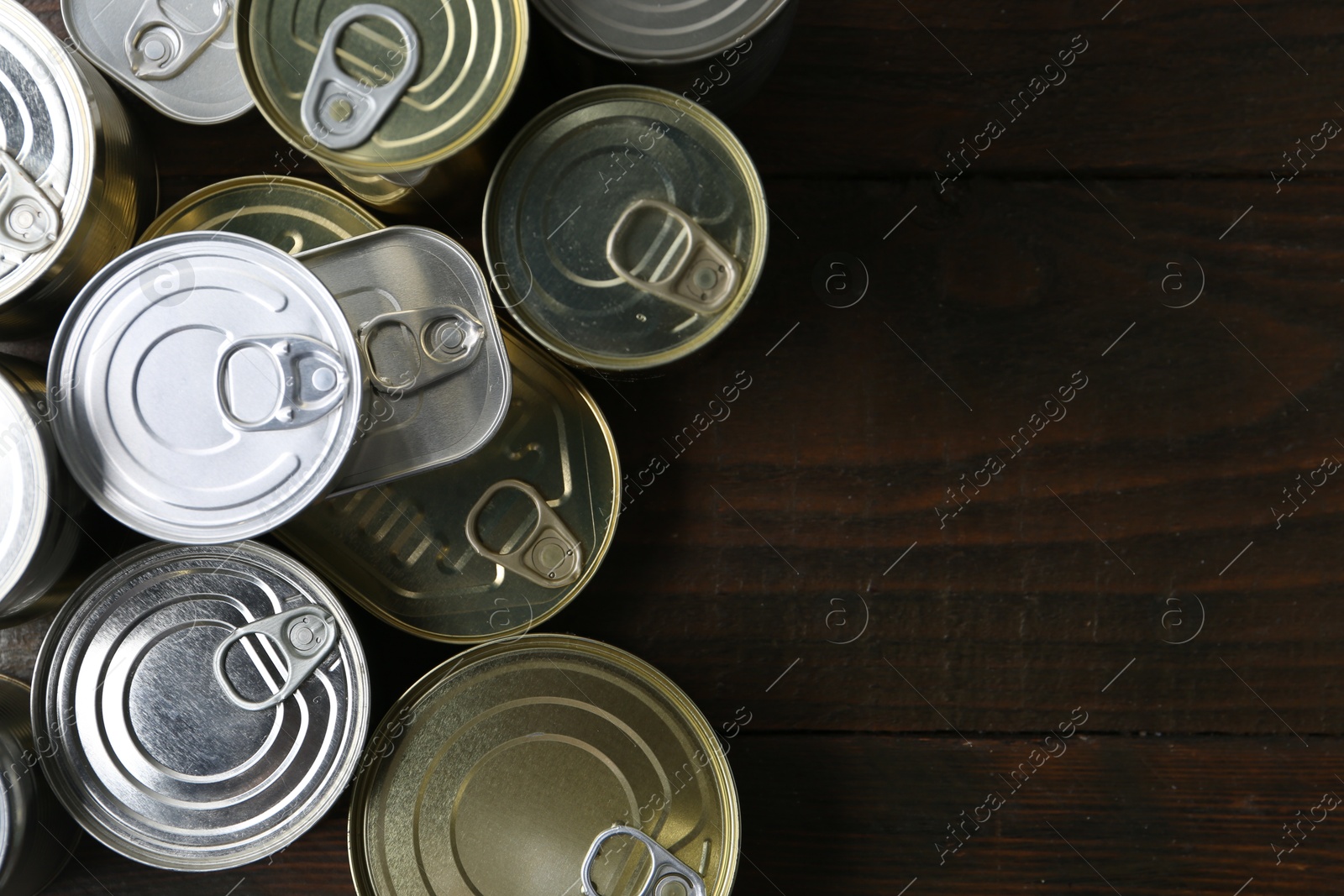 Photo of Many closed tin cans on wooden table, flat lay. Space for text