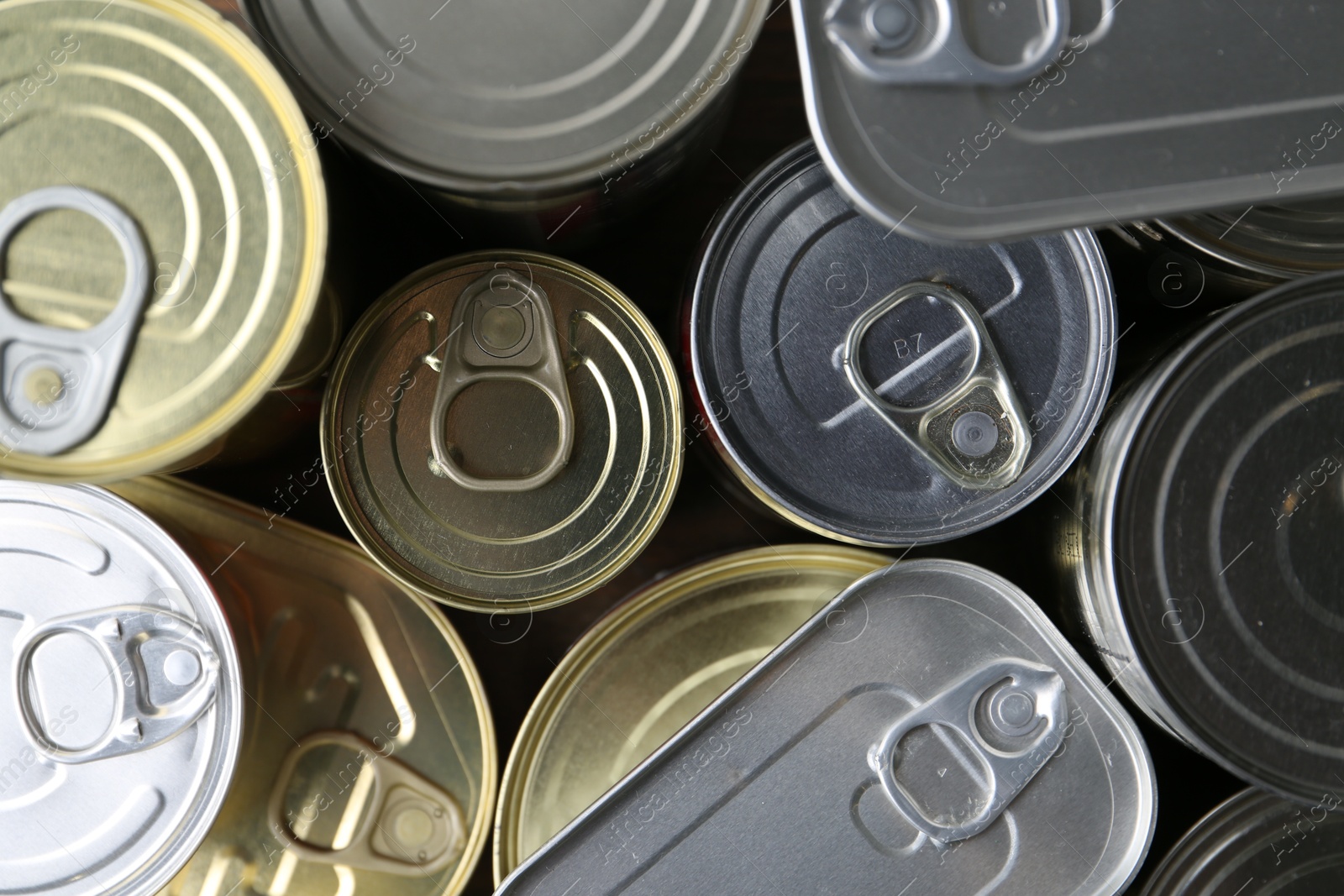 Photo of Many closed tin cans on wooden table, flat lay