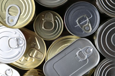 Photo of Many closed tin cans on wooden table, flat lay