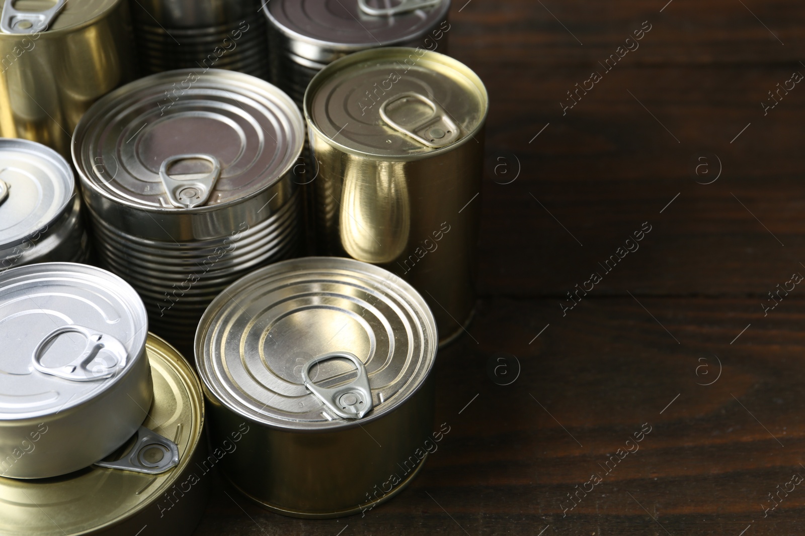 Photo of Many closed tin cans on wooden table, closeup. Space for text