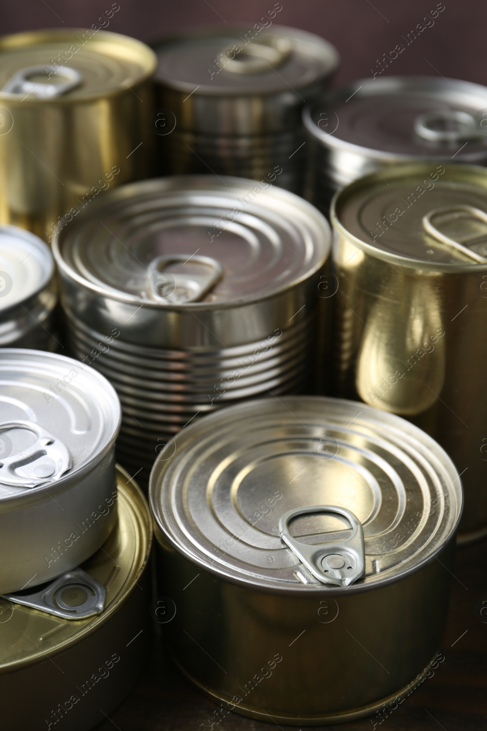 Photo of Many closed tin cans on wooden table, closeup