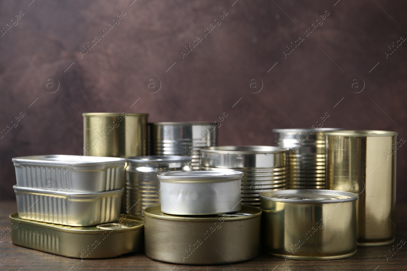 Photo of Many closed tin cans on wooden table, closeup