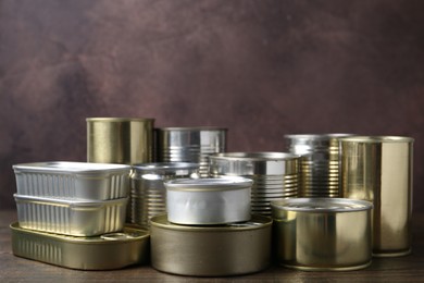 Photo of Many closed tin cans on wooden table, closeup