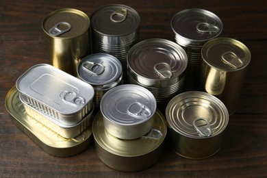 Photo of Many closed tin cans on wooden table, closeup