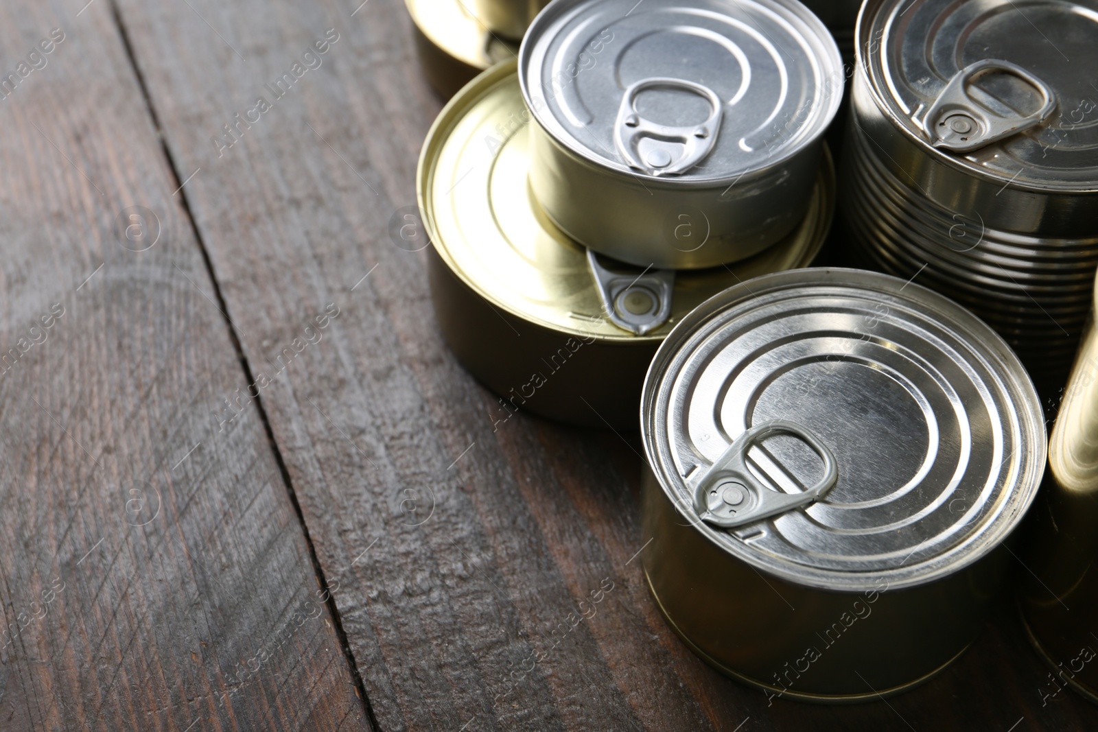 Photo of Many closed tin cans on wooden table, closeup. Space for text