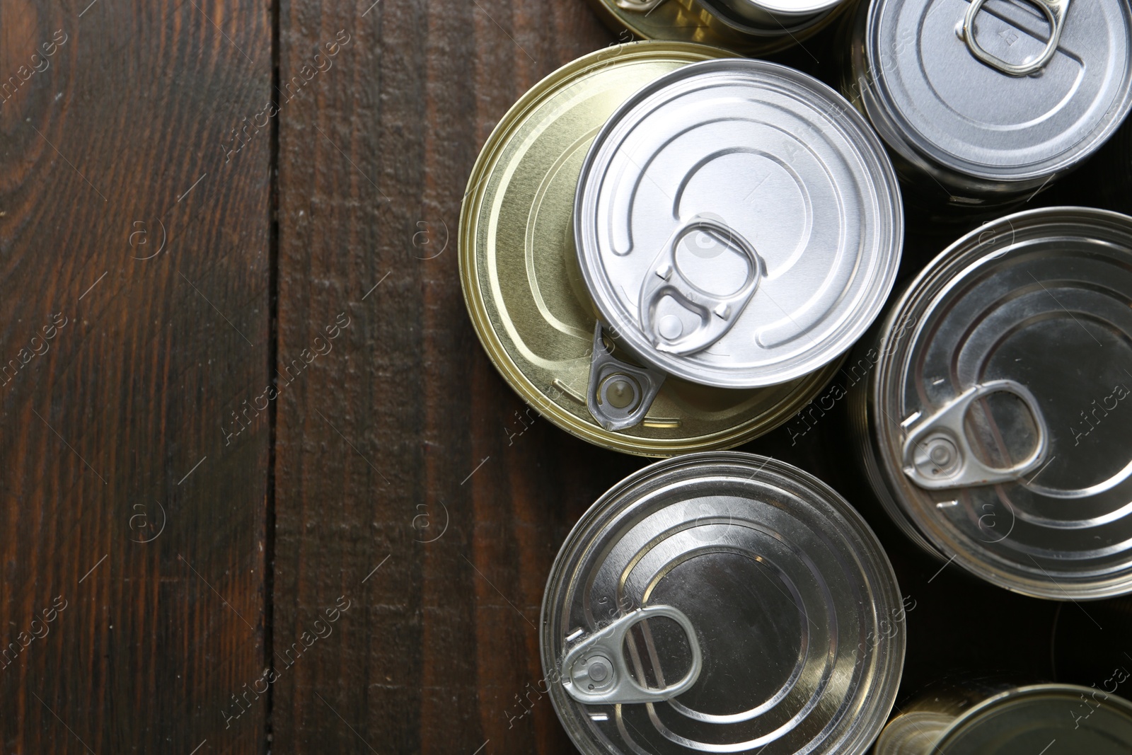 Photo of Many closed tin cans on wooden table, flat lay. Space for text