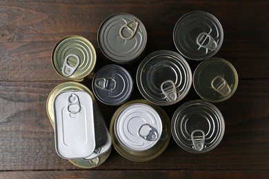 Photo of Many closed tin cans on wooden table, flat lay