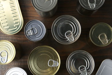 Photo of Many closed tin cans on wooden table, flat lay