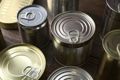 Photo of Many closed tin cans on wooden table, closeup