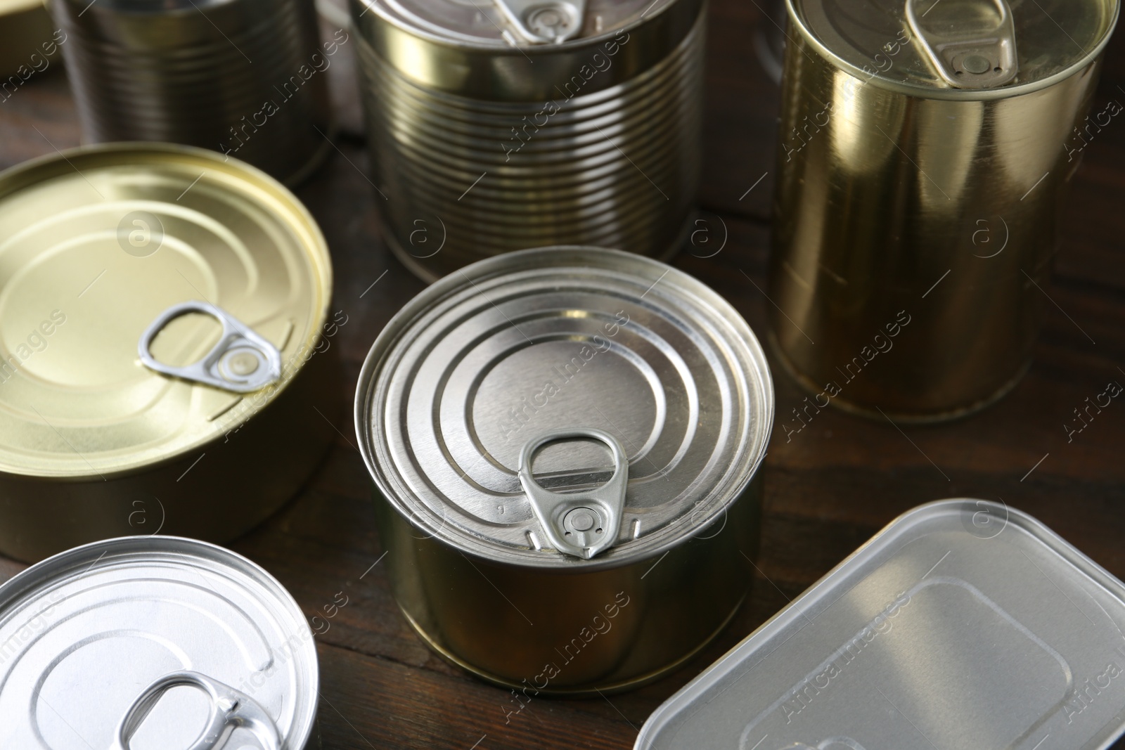 Photo of Many closed tin cans on wooden table, closeup