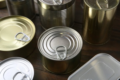 Photo of Many closed tin cans on wooden table, closeup