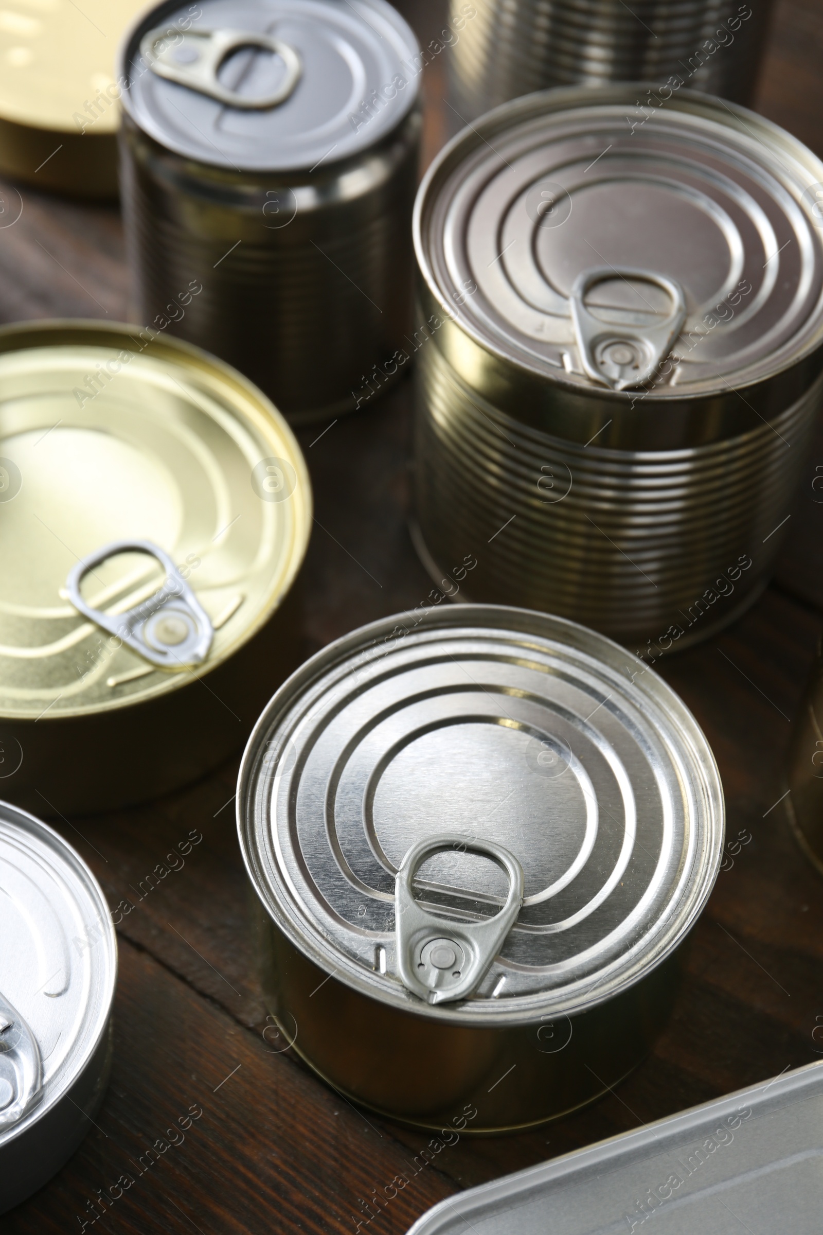 Photo of Many closed tin cans on wooden table, closeup