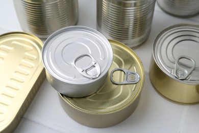 Photo of Many closed tin cans on white tiled table, closeup